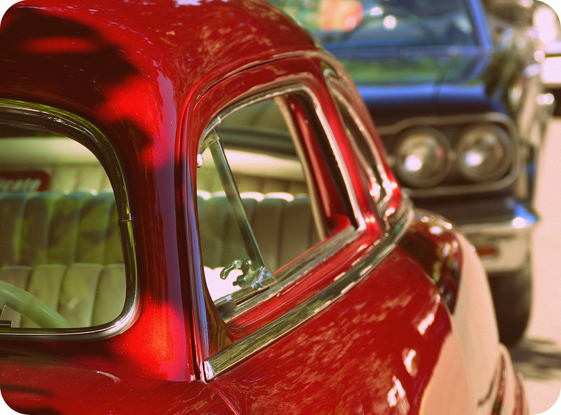 The side of a red, older car. It's well-kept.