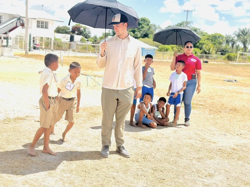 Jake Nation stands with an umbrella next to some children