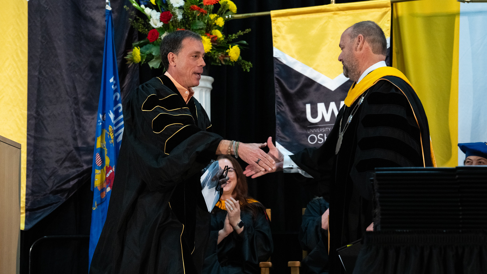 Jim VandeHei shakes someone's hand during UW-Oshkosh's graduation ceremony