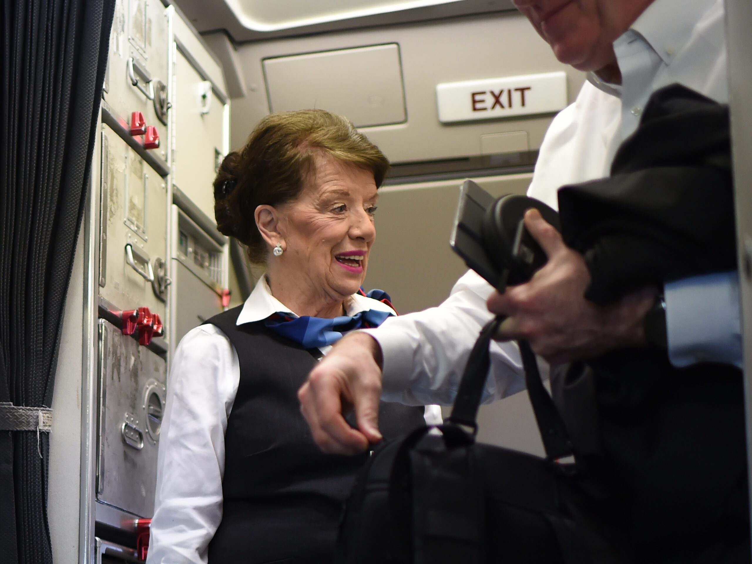 A female flight attendant greets a passenger leaving the plane.