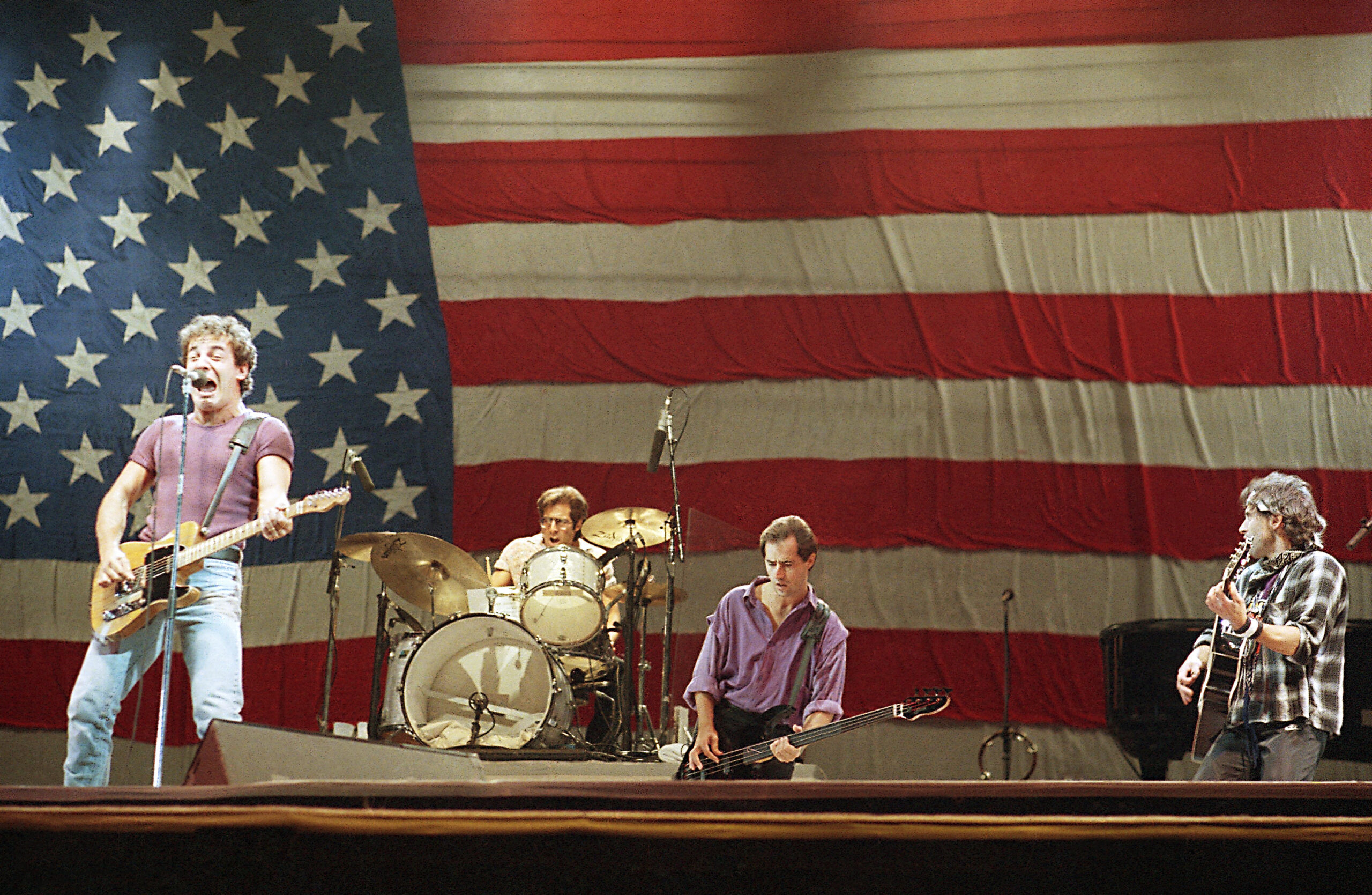 Bruce Springsteen and the E. Street Band on stage in front of an American flag