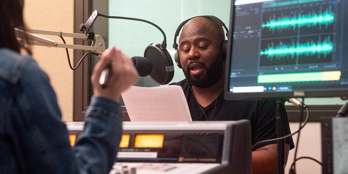 A Black man named Jesus Gregorio Smith is sitting in a Wisconsin Public Radio studio speaking into a microphone.