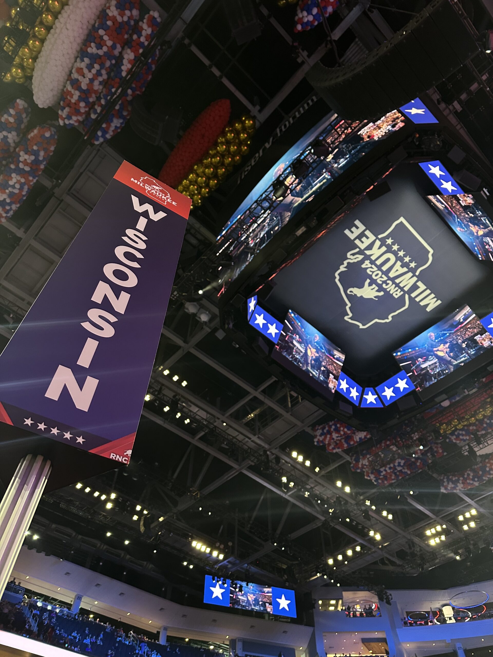 A vertical sign reading "Wisconsin" is shown on the left side of the image, with the RNC roof behind the sign on the right side of the image. The center of the ceiling shows a Wisconsin state outline with "RNC 2024 Milwaukee" written across it.