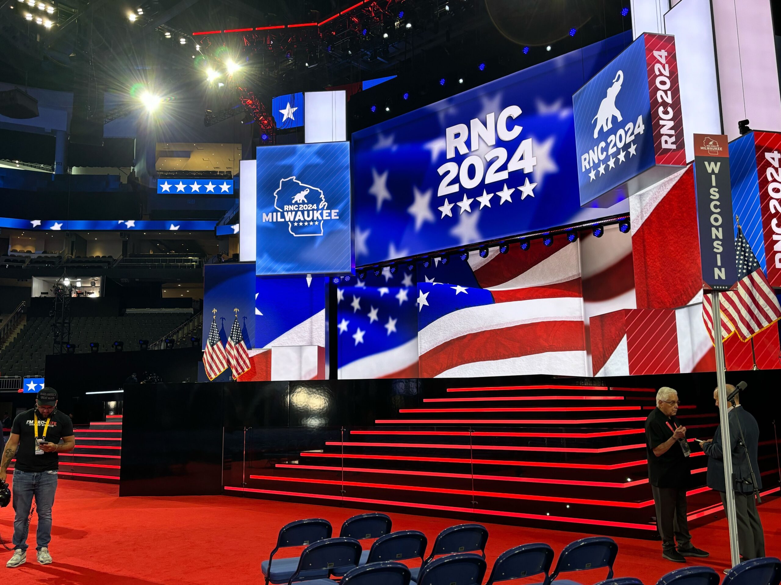 Red, white and blue signs saying "RNC 2024" surround a stage with red stairs. American flags are on either side.