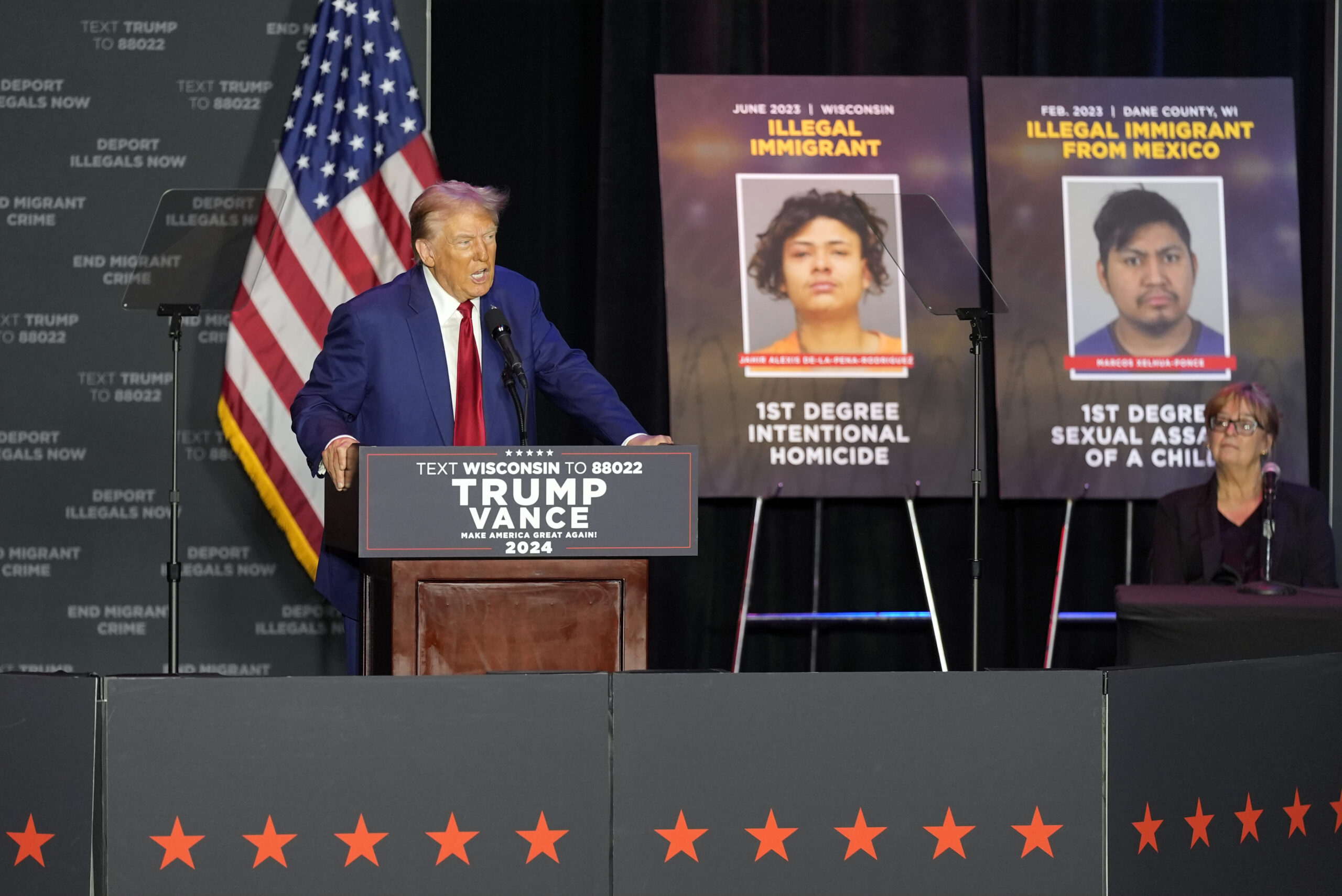 Donald Trump stands in front of posters