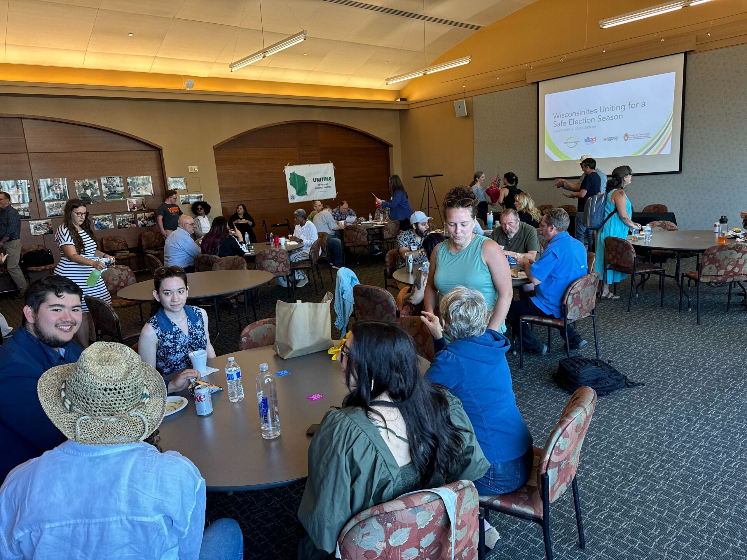 Workshop participants sit and talk around circular tables in a conference room.