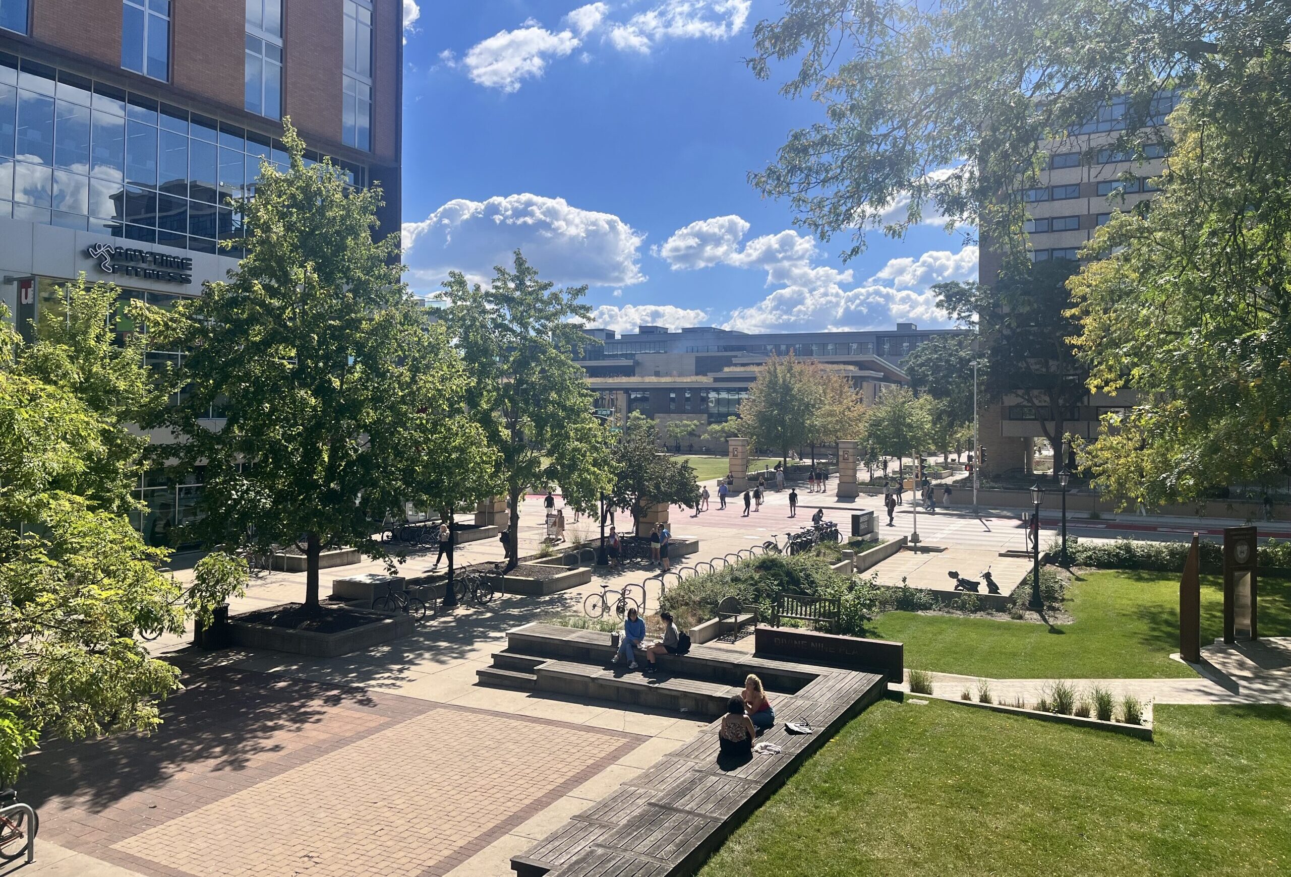 Trees line East Campus Mall in Madison with a blue sky and clouds in the background