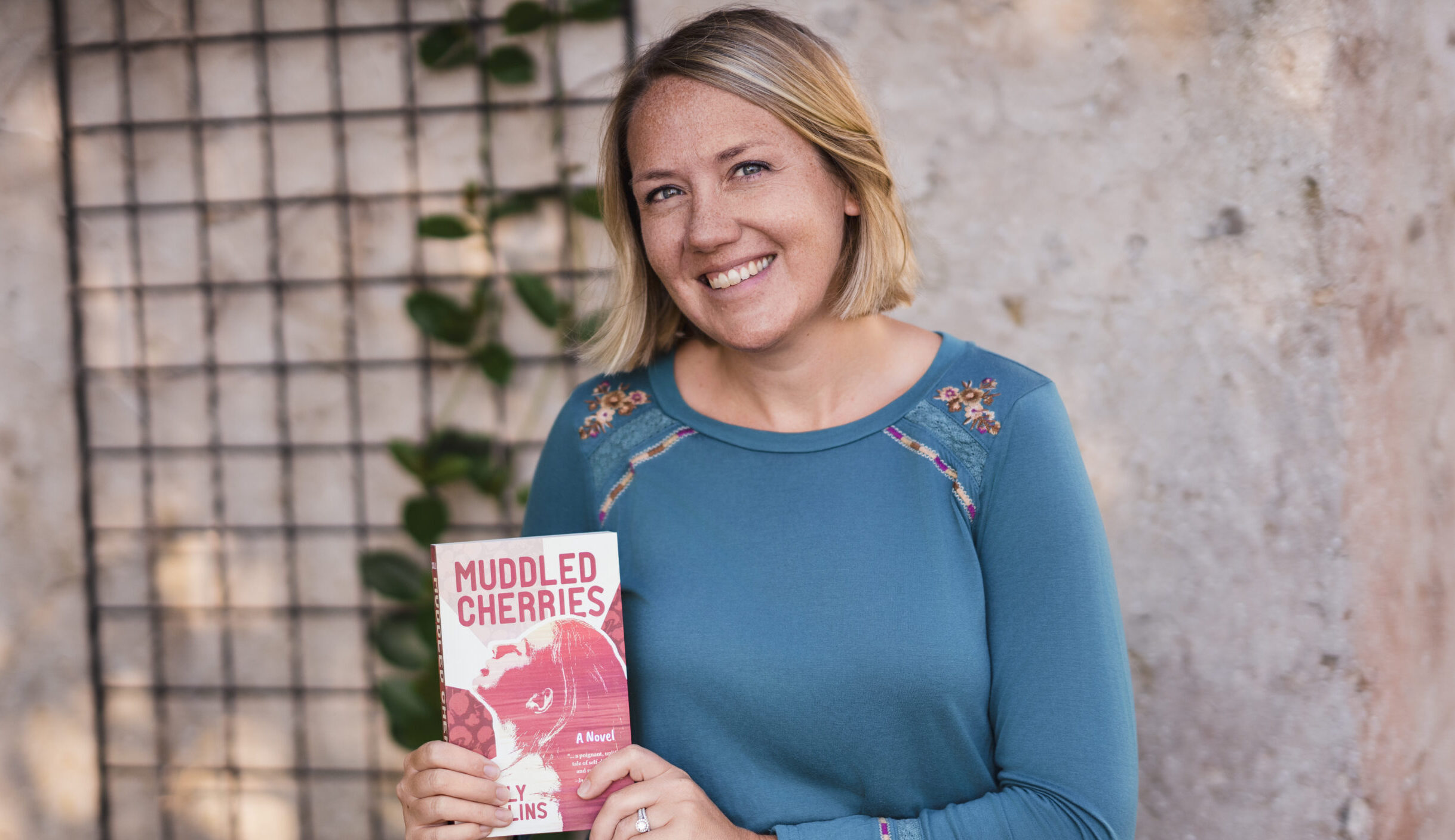 Author Sally Collins poses with a copy of her first novel, "Muddled Cherries."