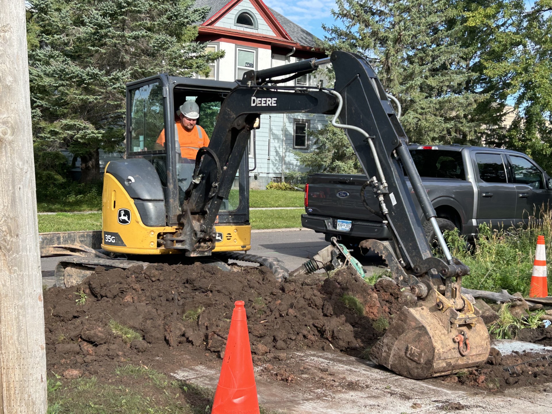 A yellow bulldozer digs into the dirt in front of a house