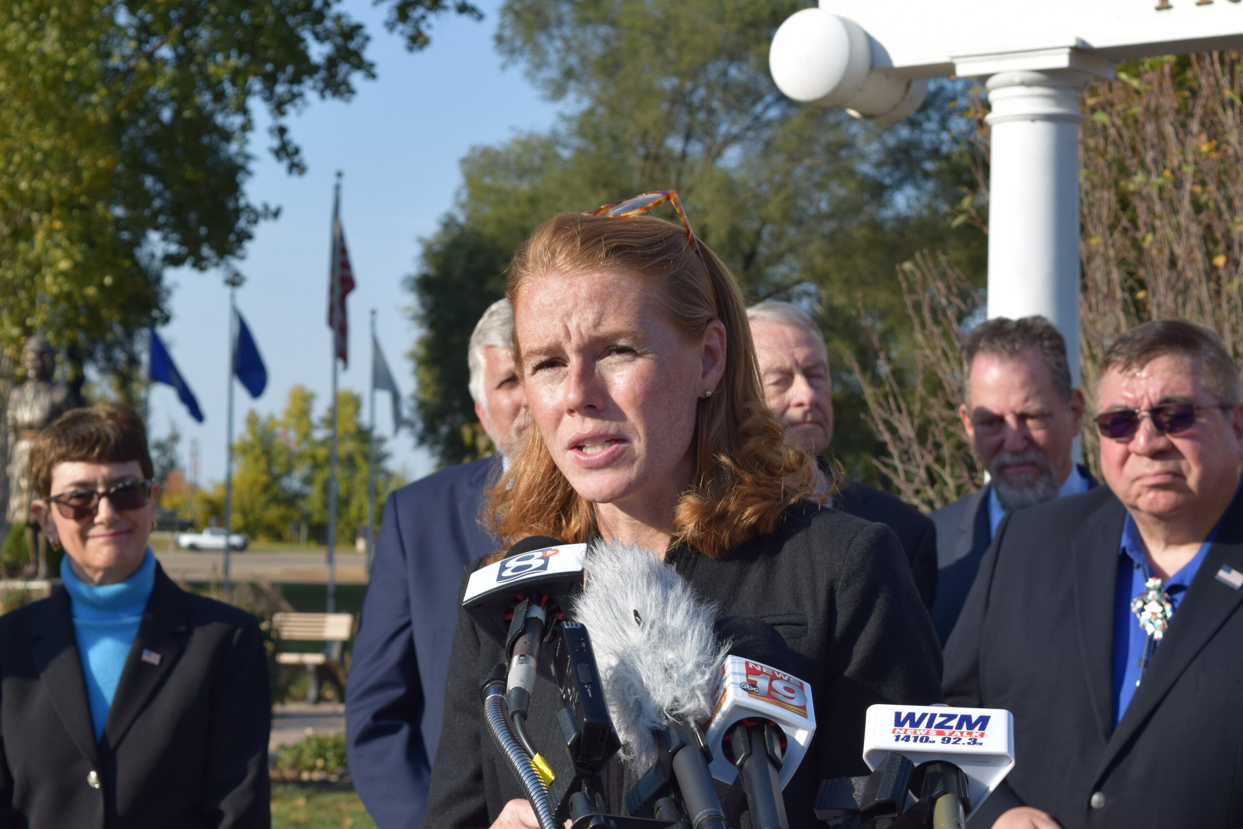 Cooke speaks into cluster of microphones in a public park