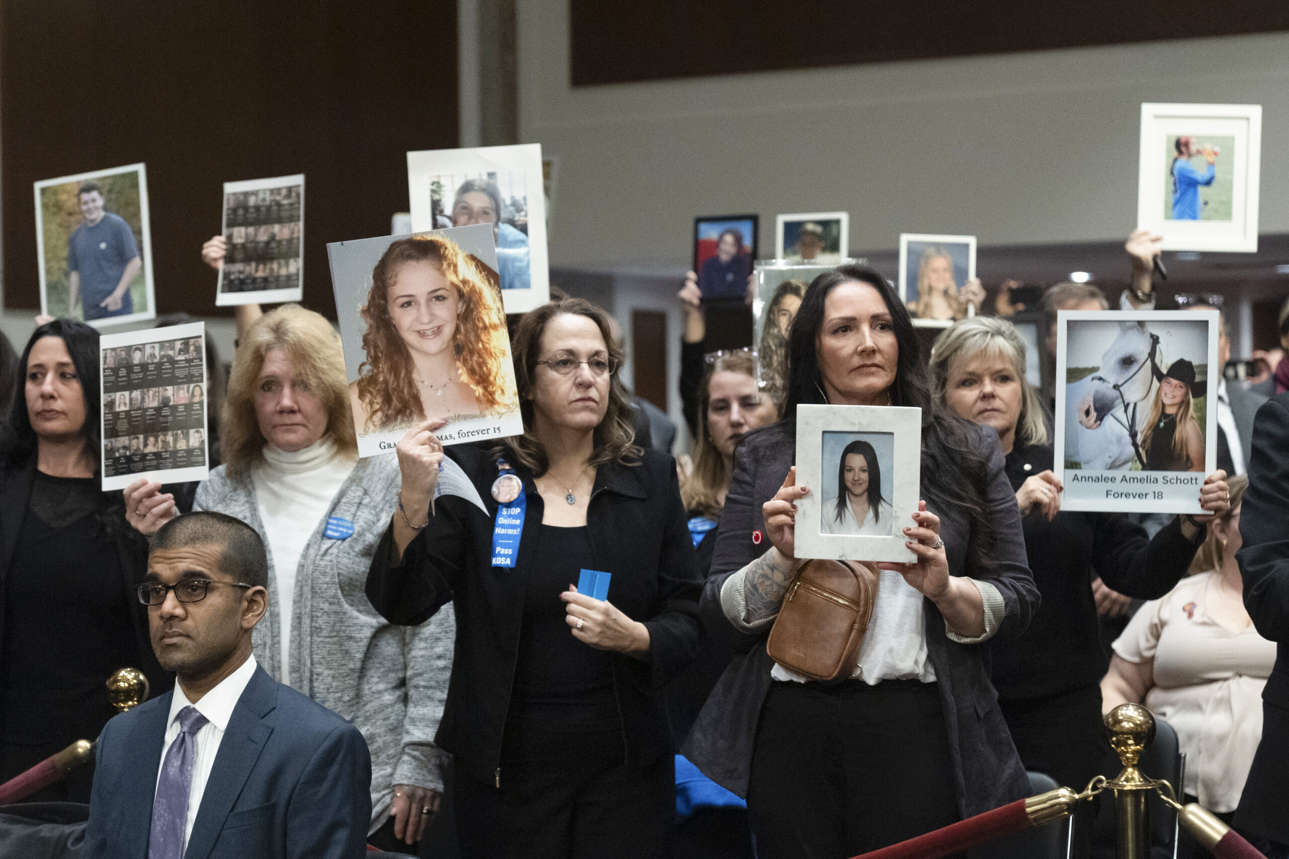 People hold up photos of their loved ones during the Senate Judiciary Committee's hearing on online child safety