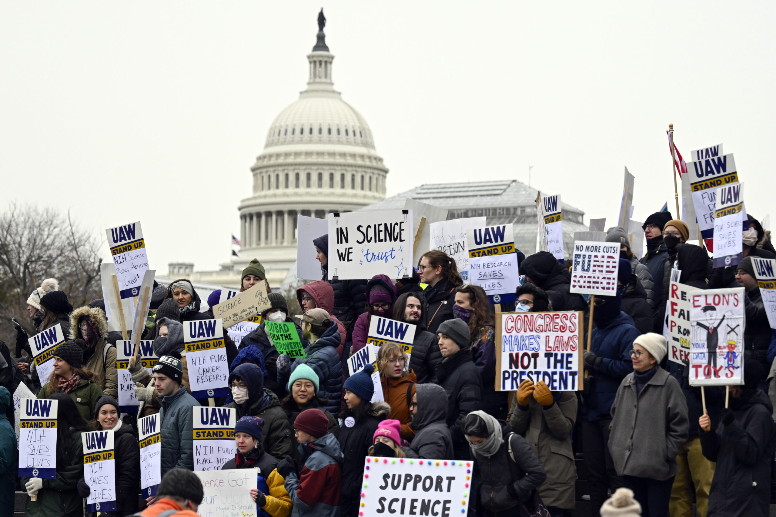 A large group of people gathered in front of the U.S. Capitol building holding signs supporting science and workers rights.