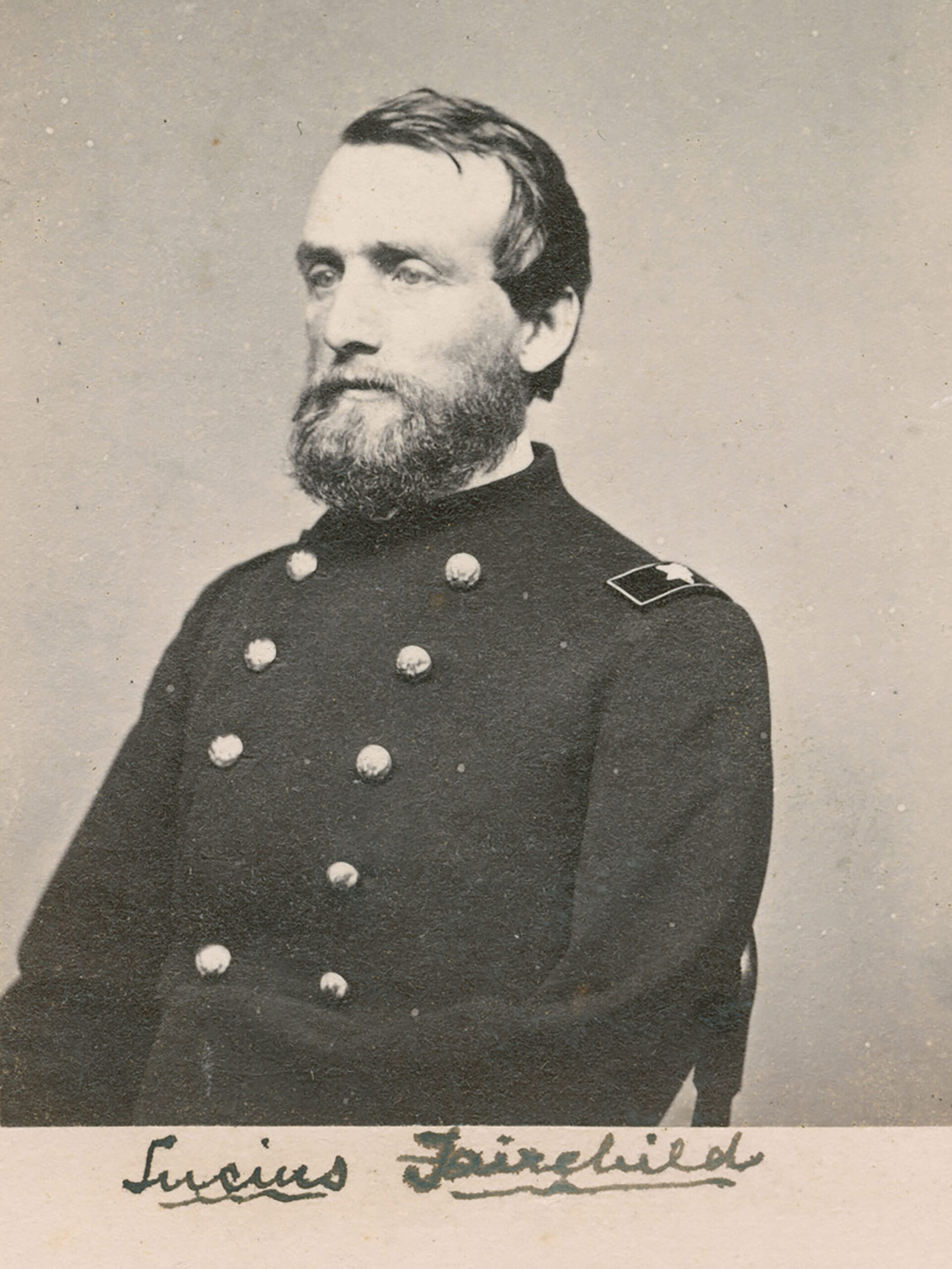 A bearded man in a 19th-century military uniform with buttons poses for a portrait. A signature is visible at the bottom.