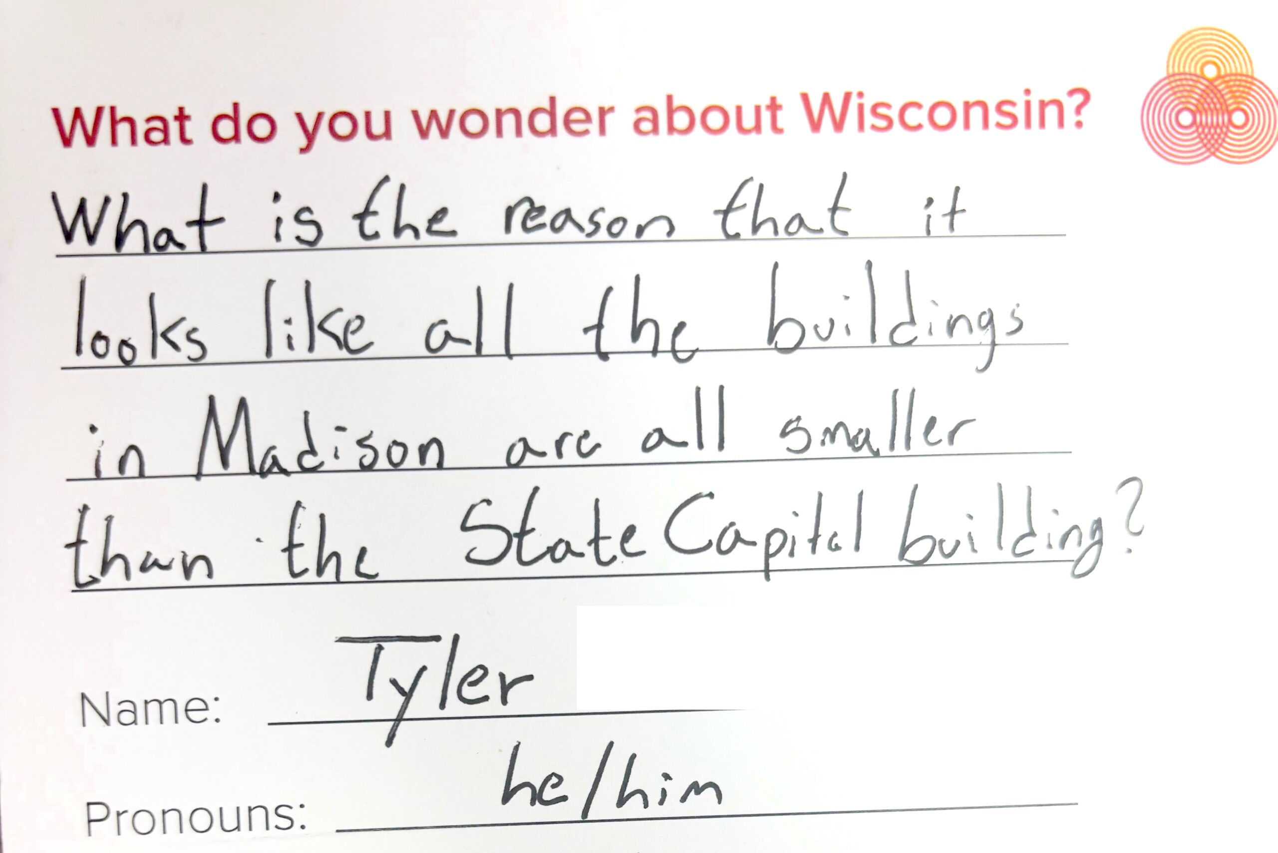 A handwritten note asking why all buildings in Madison appear smaller than the State Capitol. The name Tyler and pronouns he/him are below.